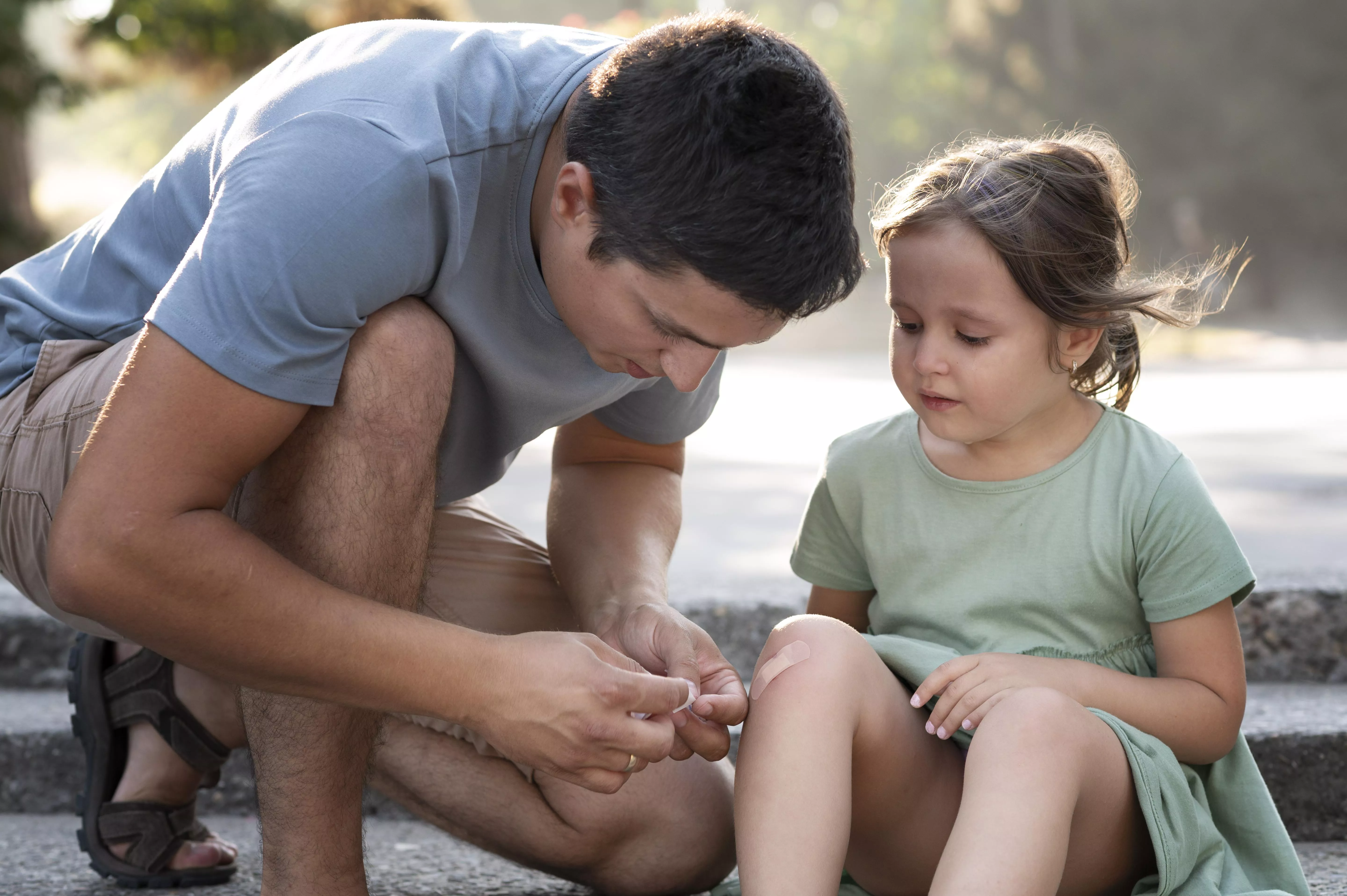 Un padre cura una pequeña herida a su hija. Imagen de freepik