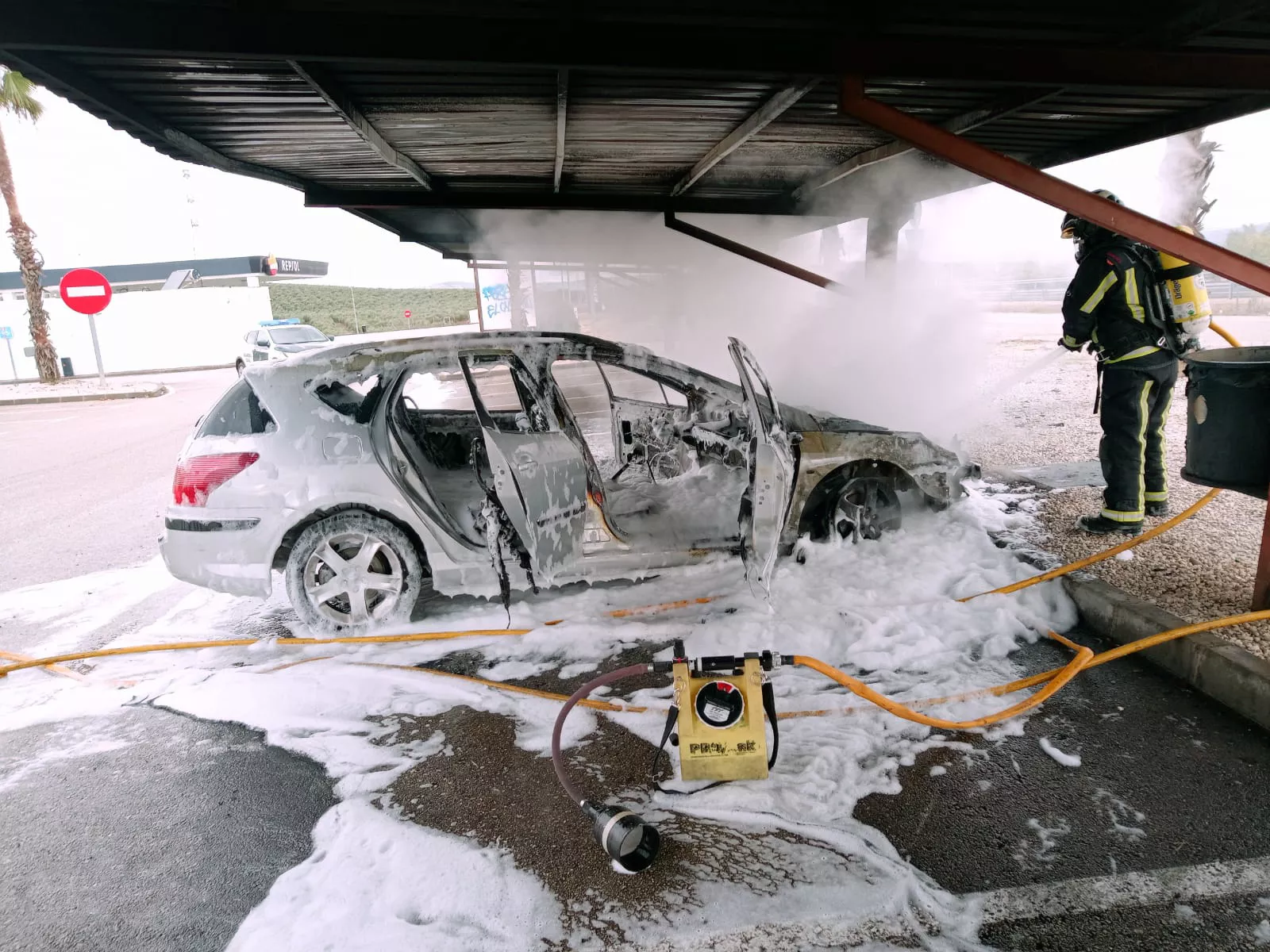 Los bomberos apagan las últimas llamas en el motor del vehículo siniestrado