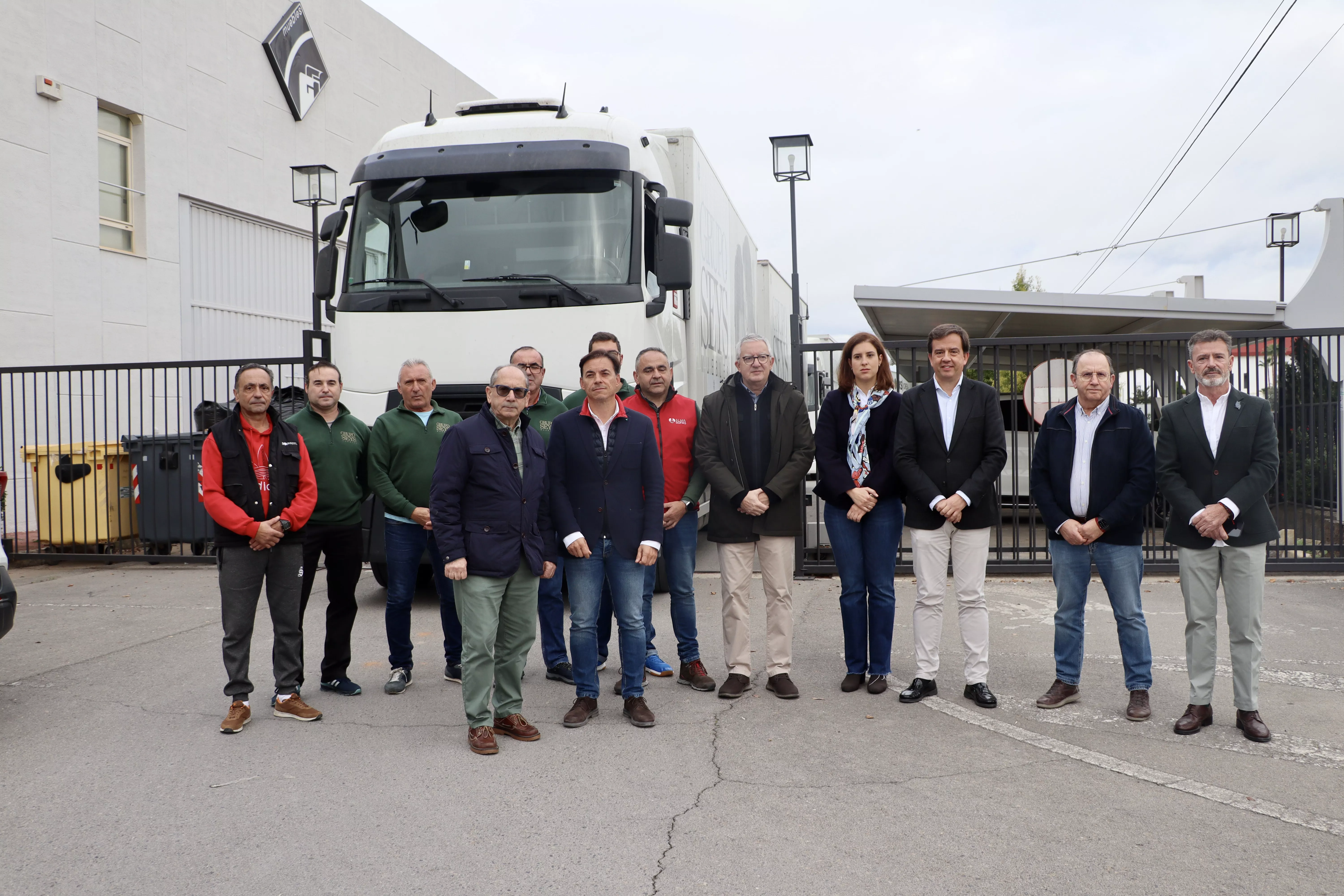 Empresarios y conductores junto al alcalde de Lucena, momentos antes de la salida del convoy de muebles con destino a Valencia